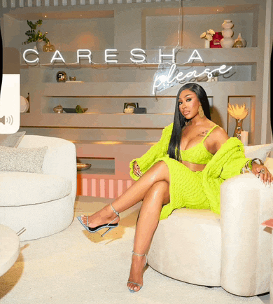 a woman in a neon green dress sits on a chair under a caresha please sign