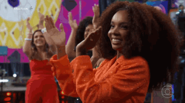 a group of women are dancing in front of a large screen that says ' acesso brasil ' on it