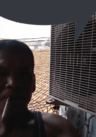 a man smoking a cigarette next to a fan