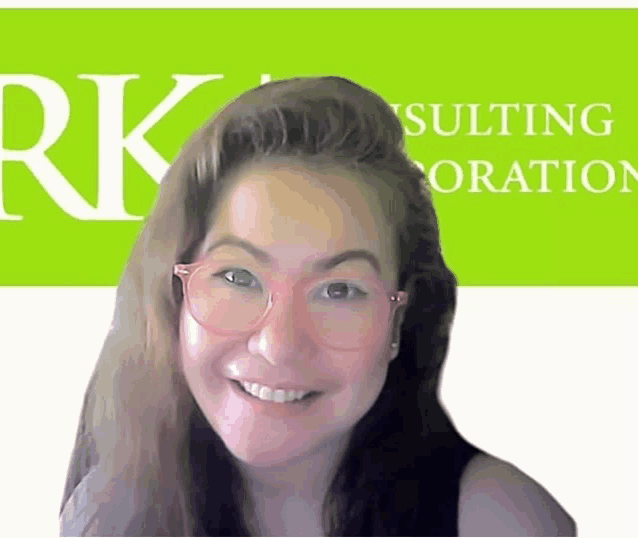 a woman wearing pink glasses is smiling in front of a green rk consulting logo