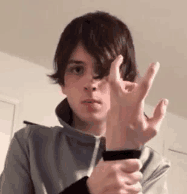 a young man is making a hand gesture with his fingers .