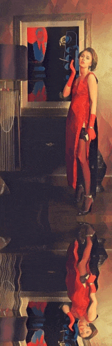 a woman in a red dress is standing in front of a dresser