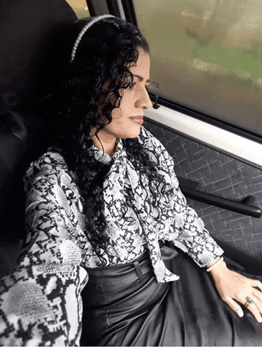 a woman with curly hair wearing a headband and a snake print shirt