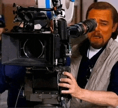 a man is holding a camera in front of his face and looking through it