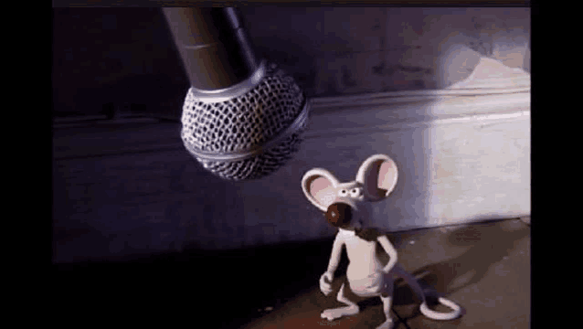 a cartoon mouse is standing next to a microphone with a red ball in its mouth .