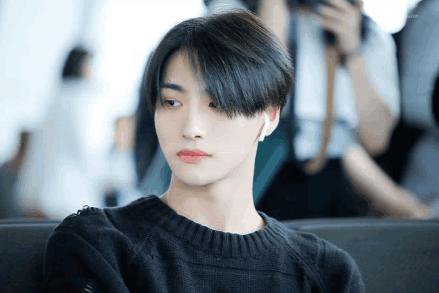 a young man wearing a black sweater and red lipstick is sitting on a couch