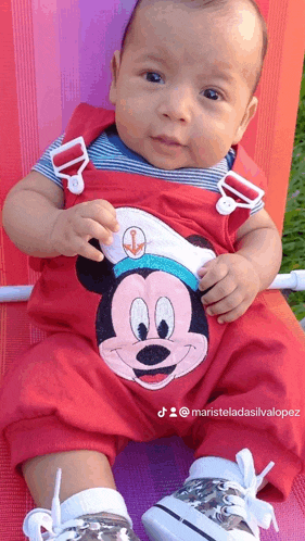 a baby wearing a red mickey mouse outfit