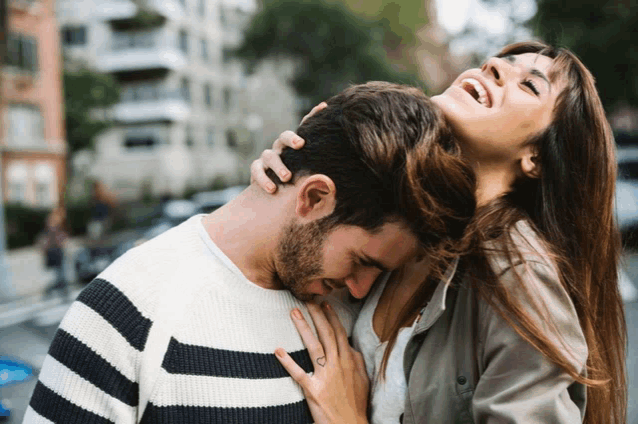 a woman holds a man 's neck and laughs