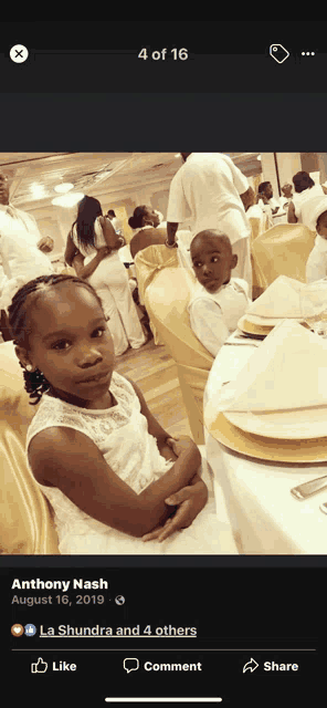 a little girl in a white dress is sitting at a table in a photo taken by anthony nash