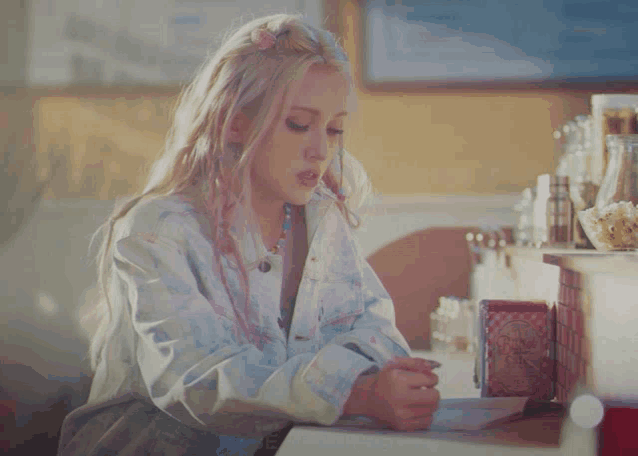 a woman sitting at a counter writing in a notebook