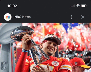 a phone screen shows a picture of a man holding a trophy with the time 10:02