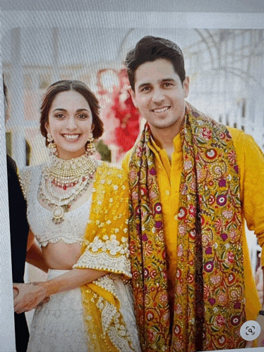 a man in a yellow shirt and a woman in a white dress are posing for a photo