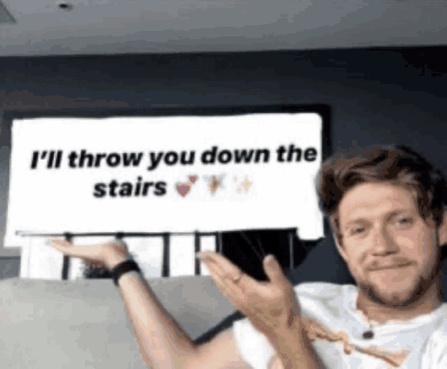 a man is holding up a sign that says i 'll throw you down the stairs