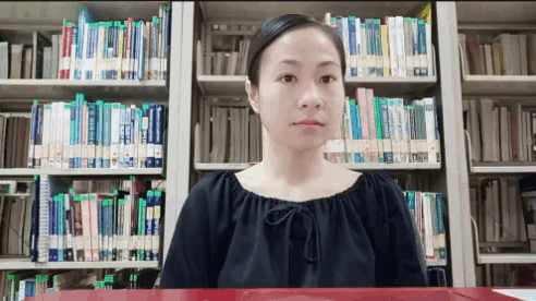 a woman stands in front of a bookshelf with a book titled ' a brief history of the world '