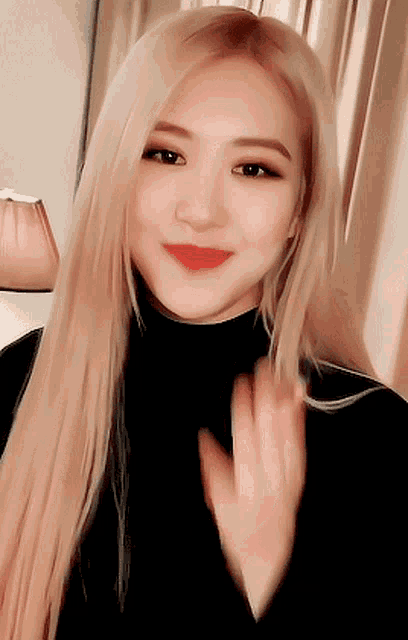 a woman with long blonde hair wearing a black turtleneck and red lipstick