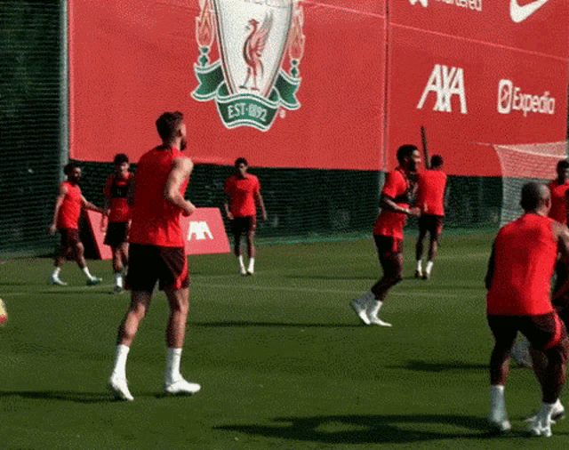 a group of soccer players are practicing in front of a large red sign that says ' axa expedia ' on it