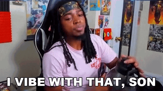 a man with dreadlocks is sitting in a chair holding a video game controller and saying `` i vibe with that son ''