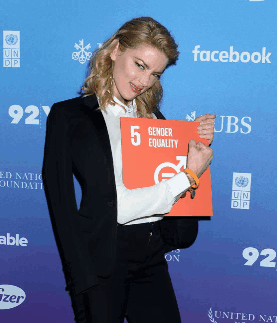 a woman in a suit holds up a sign that says gender equality