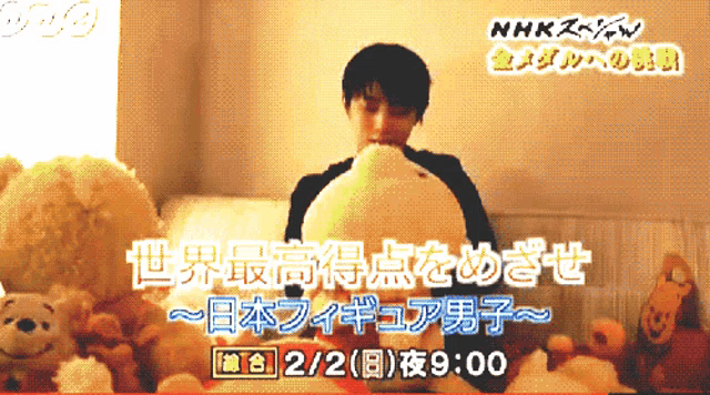 a man is holding a stuffed animal in front of a sign that says ' nhk ' on it