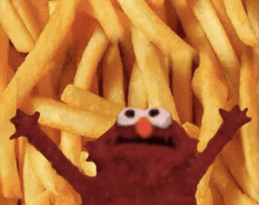 elmo is in a pile of french fries with his arms outstretched