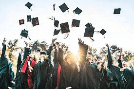 a large group of graduates are throwing their caps in the air .