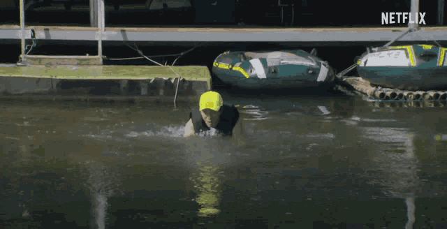 a man in a yellow hat is swimming in a body of water with a netflix logo in the corner