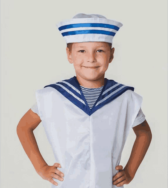 a young boy dressed in a sailor 's outfit with his hands on his hips