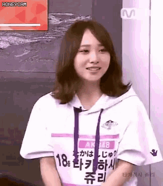 a woman wearing a hoodie and a white shirt with chinese writing on it is smiling .