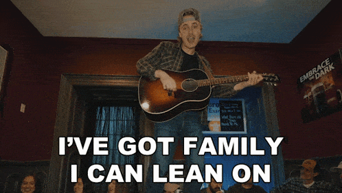 a man playing a guitar with the words " i 've got family i can lean on " above him