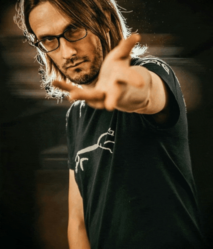 a man wearing glasses and a black shirt with a horse on it is making a peace sign