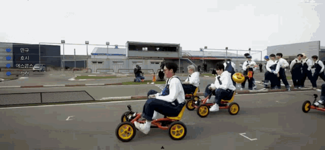 a group of people are riding go karts on a road with a sign that says ' a ' on it