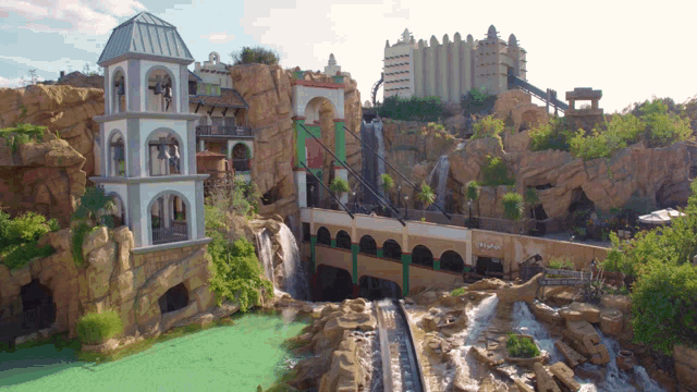 a roller coaster with a waterfall in the background and a building that says ' eiffel tower ' on the side