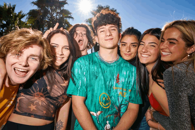 a group of young people posing for a picture with one wearing a green shirt with a smiley face on the front