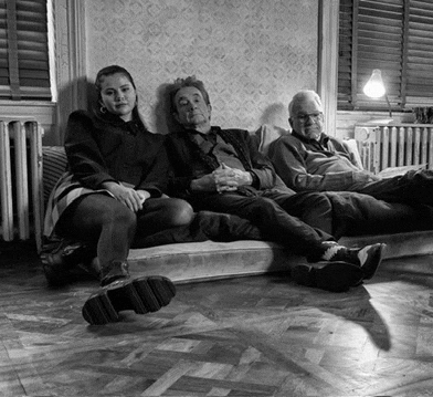 two men and a woman are sitting on a couch in a black and white photo