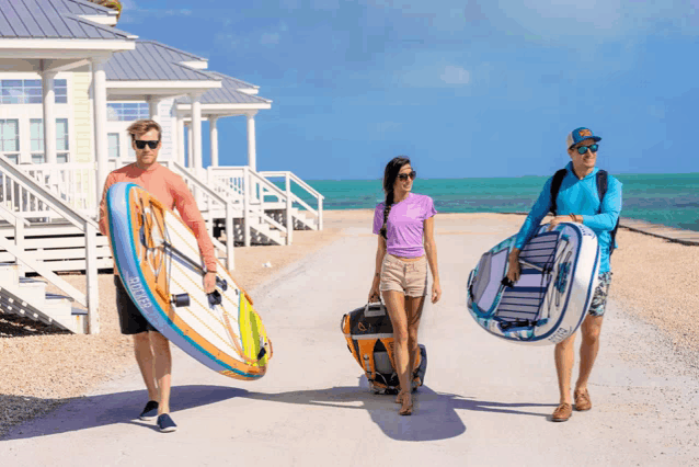 a man carrying a surfboard and a woman carrying a kayak with the word kayak on the side