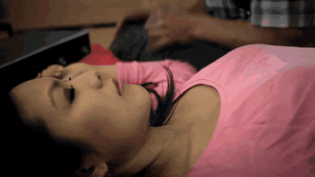 a woman in a pink shirt is laying on her stomach