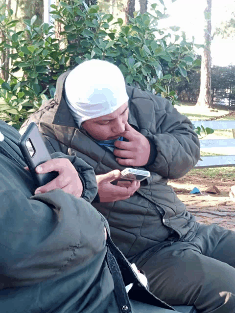 a man wearing a bandana looks at his cell phone