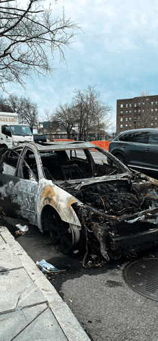 a burned out car is parked on the side of the road in front of a white truck that says oscar rabbit