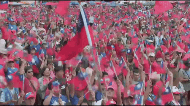 a crowd of people holding up pink flags with a man wearing a shirt that says ' nc ' on it