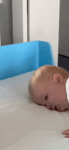 a baby is laying on a crib with his head on the mattress .