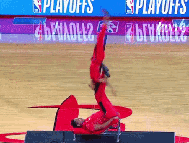 a man is doing a handstand on a basketball court in front of a sign that says " playoffs "