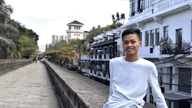 a young man in a white shirt stands in front of a building that says ' a ' on the side