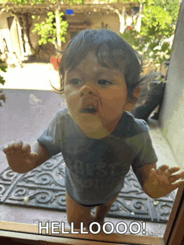 a baby is standing in front of a door with the words hellooo on it