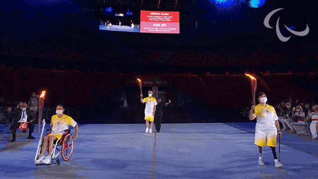 a woman in a wheelchair is holding a torch in front of a sign that says ' official 's guide '