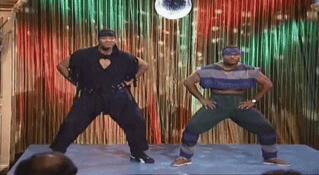 two men are dancing in front of a disco ball on a stage