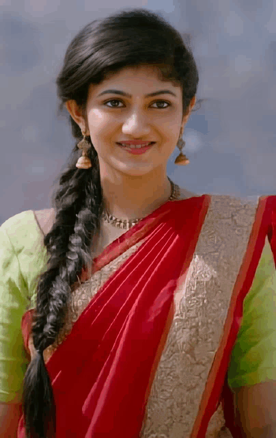 a woman wearing a red saree and a green blouse