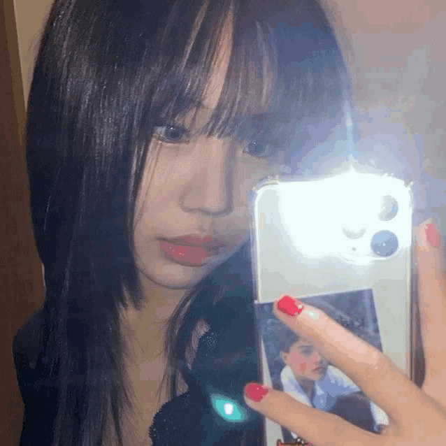 a girl with red nails takes a selfie in the mirror