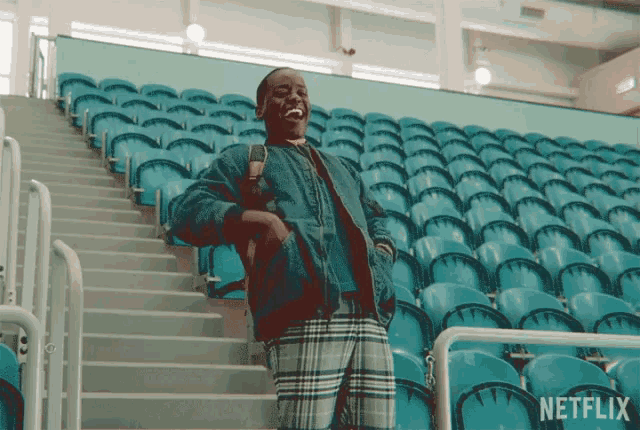 a man is standing on a set of stairs in front of a row of blue seats that say netflix on them