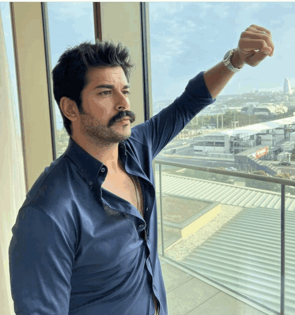 a man with a mustache is standing in front of a balcony