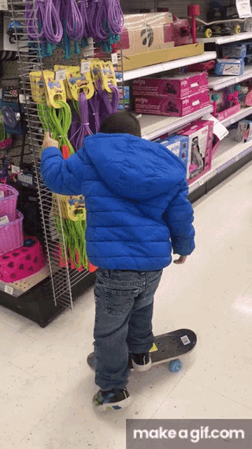 a young boy is standing on a skateboard in a store with a make a gif.com watermark at the bottom